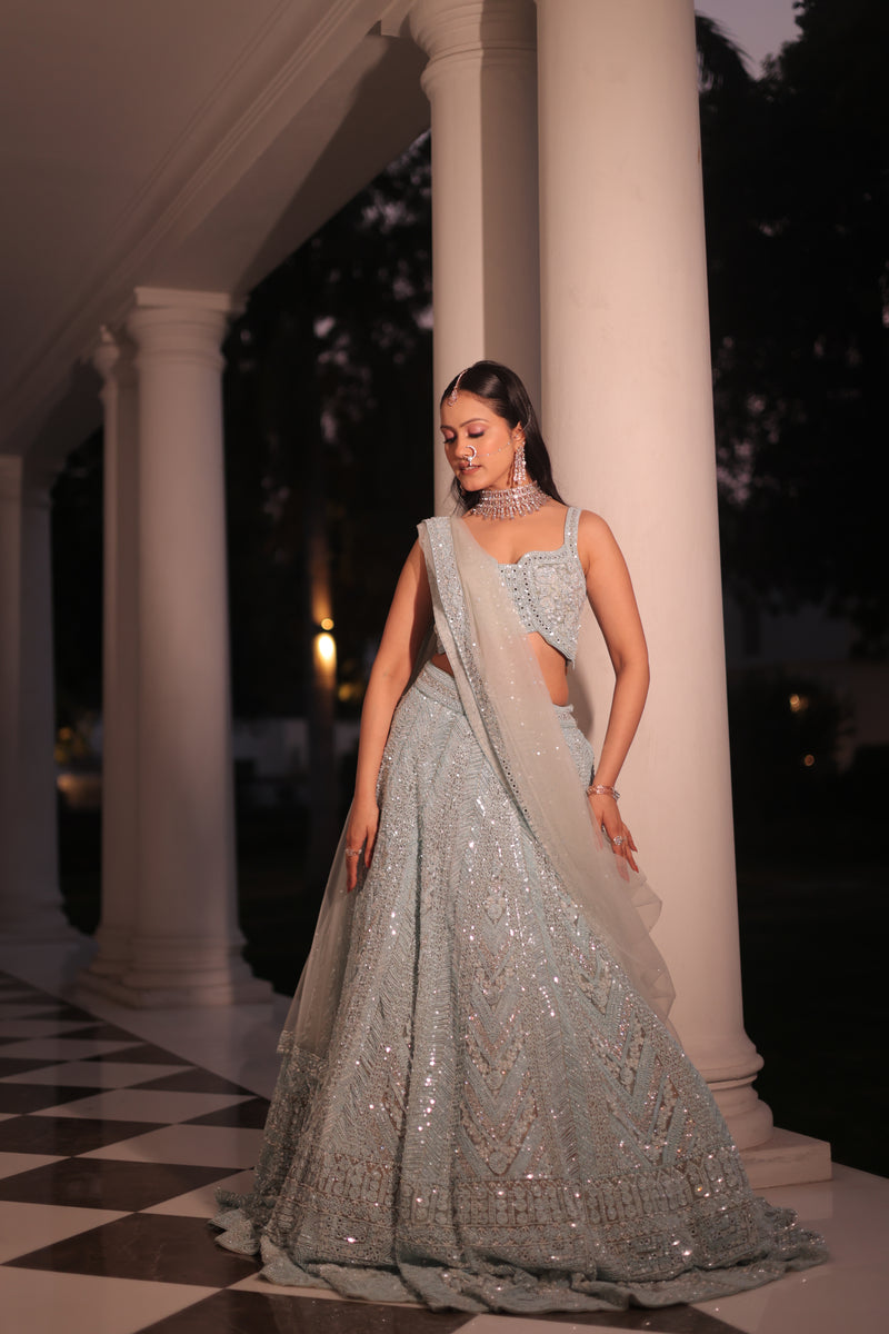 AQUA BLUE NET LEHENGA EMBELLISHED WITH SEQUINS,CUT DAANA AND A TOUCH OF MIRROR WORK